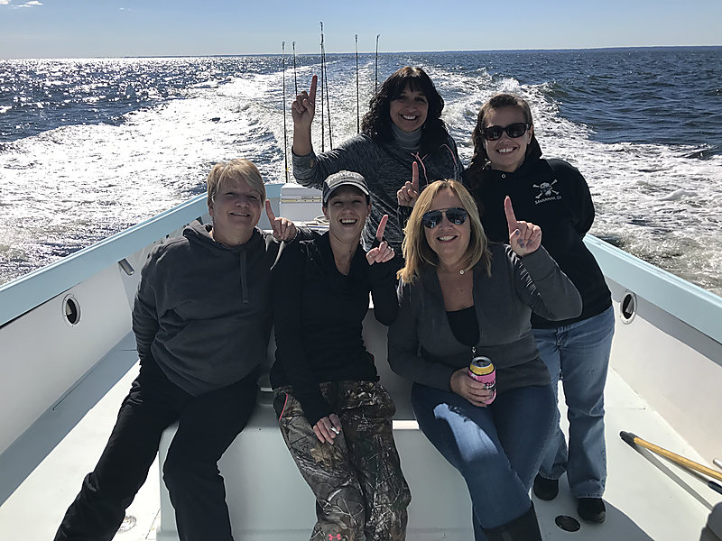 Five friends on the Class Act deck with the wake behind them