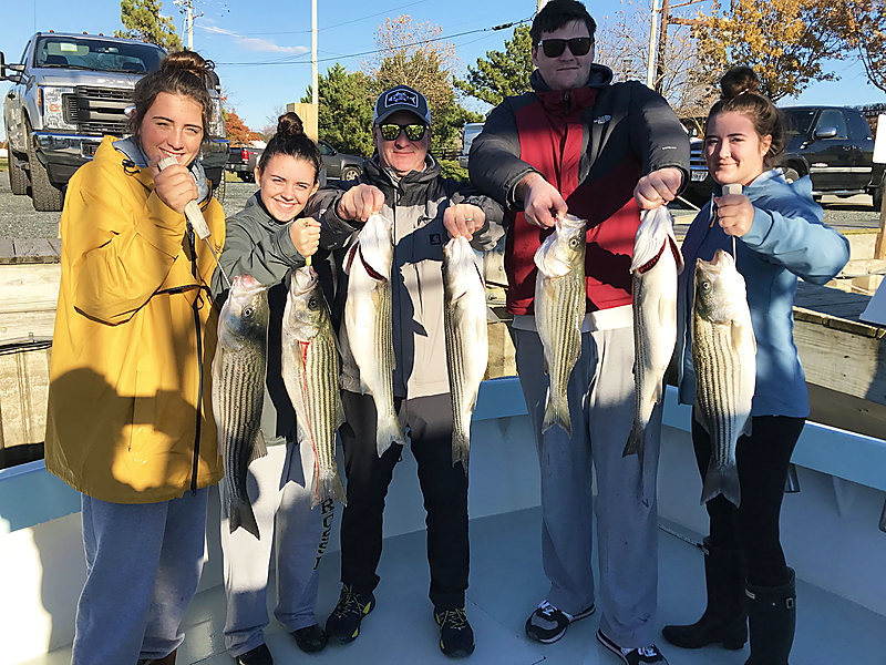 A family of five on the dock, each holding a rockfish