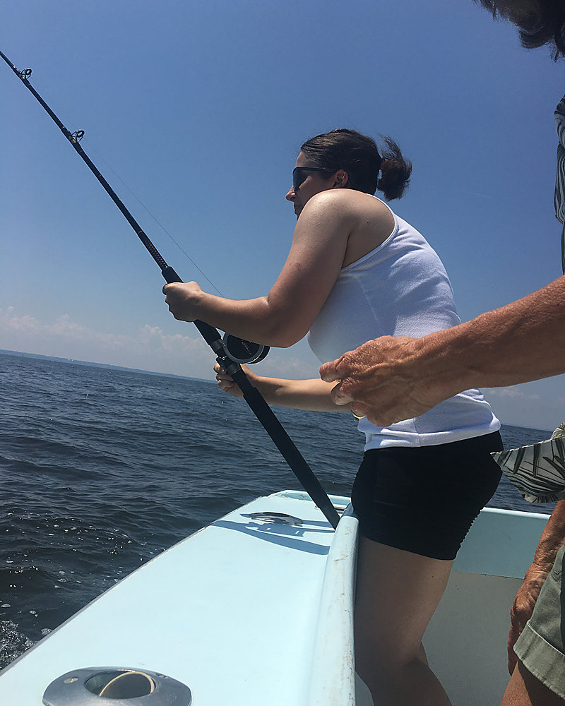 A young woman working a trolling rod over the stern
