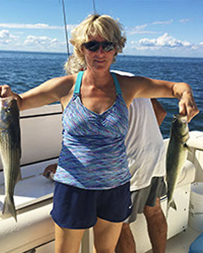 A woman holding up a rockfish in each hand